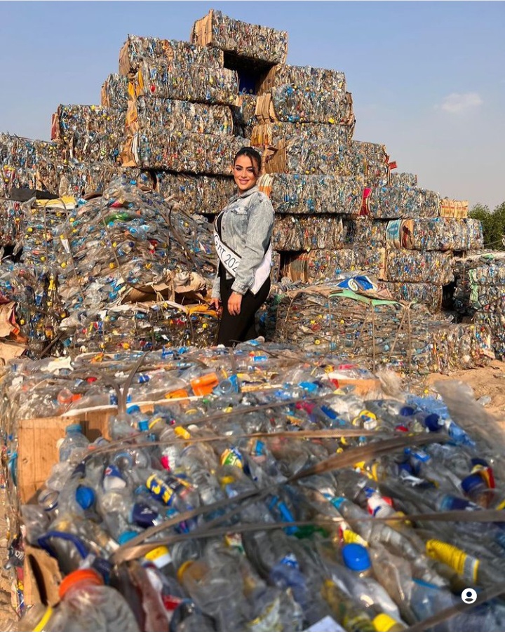 هاجر محمد تقف بجوار جبل من النفايات تبع منظمة لحماية نهر النيل لتشجيعهم وهى ترتدي شريط التكريم بملابس كاجوال