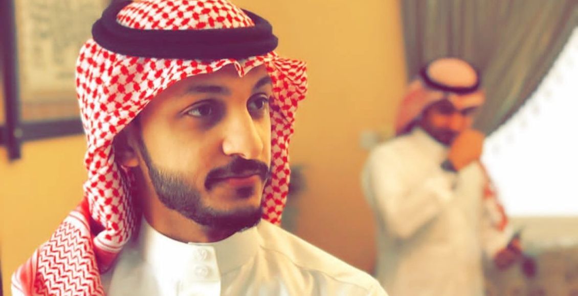 صالح اوبلز مرتديا جلابية وعقال سعودي في غرفة.