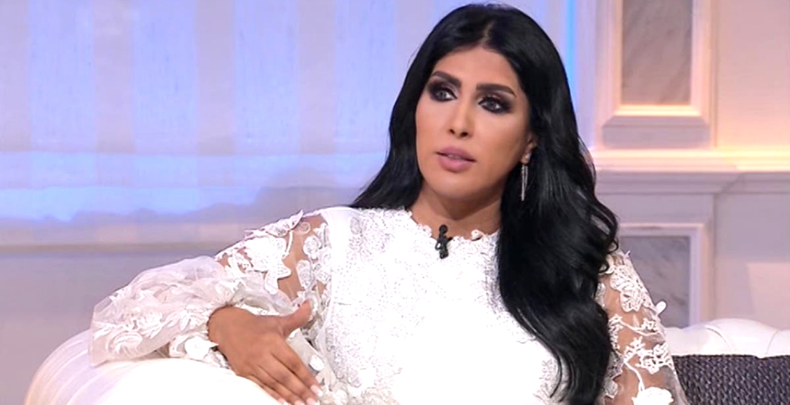 الممثلة زهرة عرفات بفستان أبيض راق تجلس على كنبة في إحدى المقابلات التلفزيونية