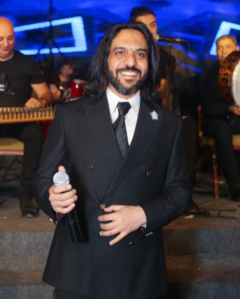 بهاء سلطان يرتدي بدلة سوداء وربطة عنق سوداء وقميص أبيض